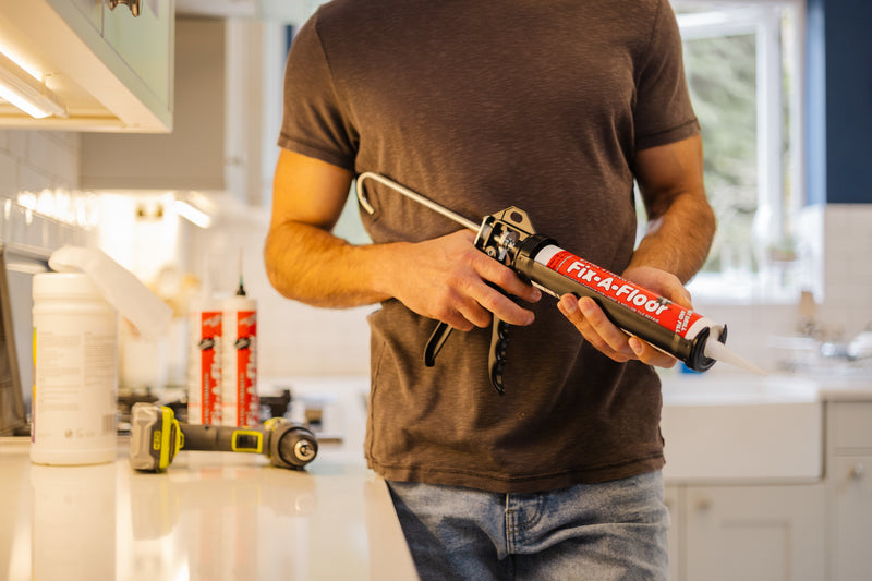Load image into Gallery viewer, Man fixing squeaky floor with fix a floor adhesive