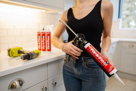 fix-a-floor caulking gun applying tile adhesive for floor repair in kitchen setting